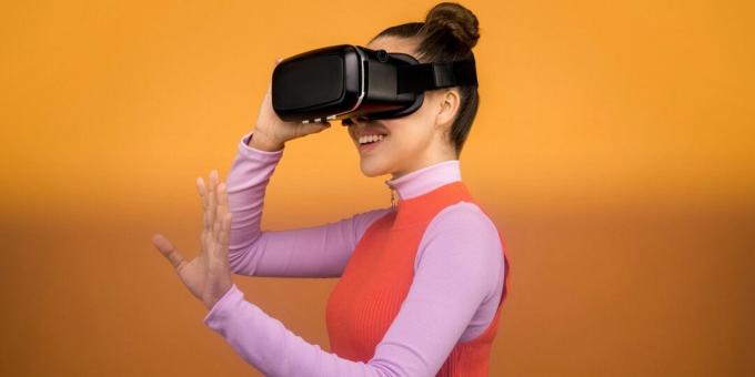 Kvinne som smiler mens hun har på seg et svart virtual reality-headset